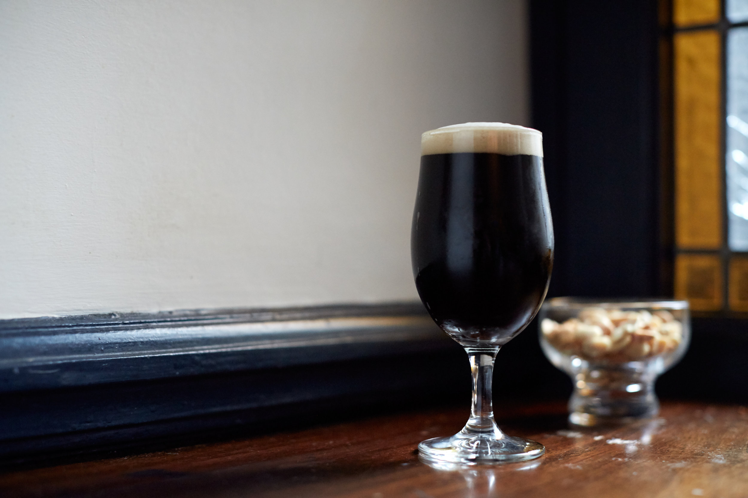 A glass of stout by the stained glass